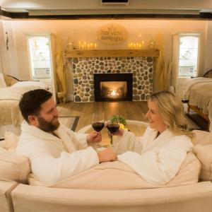 a man and woman sitting on a couch with glasses of wine at Stevenson Farms-Harvest Spa B & B in Alliston