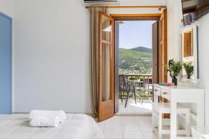 a bedroom with a door open to a balcony at White Lily in Skopelos Town +18 photos