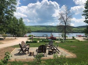 Eine Gruppe von Stühlen steht in einem Park neben einem See in der Unterkunft Cottage Place on Squam Lake - Cabins in Holderness