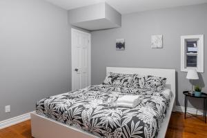 a white bedroom with a bed with a black and white comforter at Pet-Friendly Apartment on Ossington Ave in Toronto