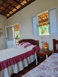 two beds in a room with two windows at Carneiro Caiçara chalés- Casinhas aconchegantes em Ubatuba in Ubatuba