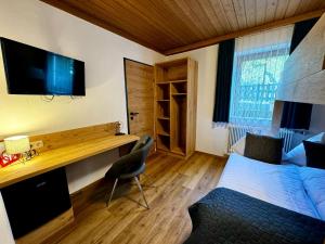 a bedroom with a bed and a desk with a television at Pension Lederergütl - Jokercard & Parkplatz inkl in Saalbach Hinterglemm