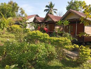 a house with a lot of plants in front of it at Anak Rinjani Guest House in Senaru