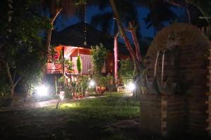 a house with lights in the yard at night at Utopia Bungalows Gili Air in Gili Islands