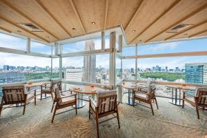 a restaurant with tables and chairs and large windows at Odakyu Hotel Century Southern Tower in Tokyo
