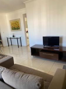 a living room with a couch and a flat screen tv at Moderno, equipado e no melhor bairro - Aquarius I in São José dos Campos