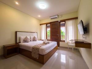 een slaapkamer met een bed, een bureau en een raam bij Ananda's Sanur by ABM in Sanur