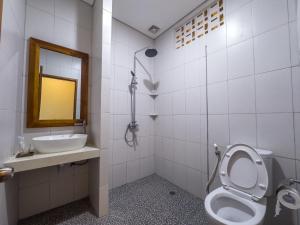 een badkamer met een toilet, een wastafel en een spiegel bij Ananda's Sanur by ABM in Sanur