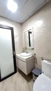 een badkamer met een wastafel, een toilet en een spiegel bij Asahi Luxstay - Tecco Elite City Apartment Thai Nguyen in Thái Nguyên