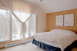 a bedroom with a bed and a large window at Chalet familial et SPA à proximité du Mont Orford in Orford +26 photos