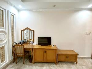 Zimmer mit einem Holzschreibtisch mit TV. in der Unterkunft Madella Hotel in Cần Thơ