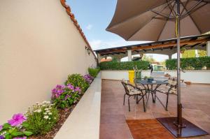 a patio with an umbrella and chairs and flowers at Apartments Villa Amfora in Rovinj