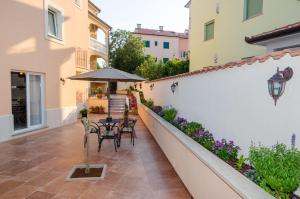 a patio with tables and chairs and an umbrella at Apartments Villa Amfora in Rovinj