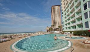 a large swimming pool next to a building and the ocean at Emerald Beach by Panhandle Getaways in Panama City Beach
