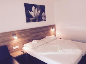 Schlafzimmer mit einem weißen Bett mit einem Kopfteil aus Holz in der Unterkunft TownVille in Flachau