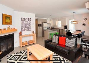 ein Wohnzimmer mit einem schwarzen Ledersofa und einer Küche in der Unterkunft Super Condo ski et vélo 2 min Mont-Ste-Anne in Beaupré