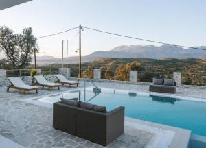 a swimming pool with couches and chairs in front of a mountain at Villa Ida in Kamilari
