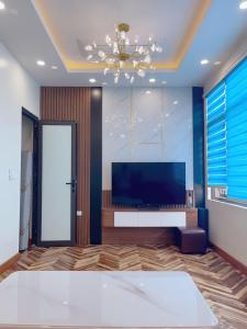 a living room with a television and a chandelier at Van villa in Hanoi