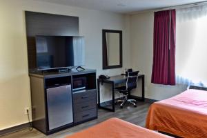 a hotel room with a television and a desk with a computer at The Maverick Motel, Main Street USA Collection by PNW Hospitality in Klamath Falls