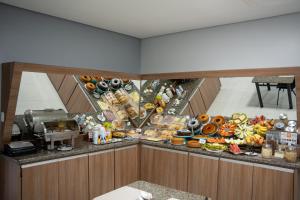 a counter with a bunch of food on it at Hotel Home in Lucas do Rio Verde
