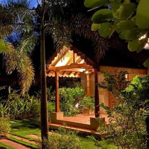 Un jardín con un cenador con plantas y árboles. en FarmStay FamilyVilla Vadodara, en Vadodara