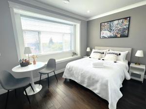 a bedroom with a white bed and a table and a window at Jennifer's House in Vancouver +8 photos