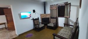 a living room with a fireplace and chairs and a tv at Pergamino GUEST HOUSE in Pergamino