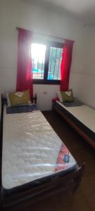 two beds in a small room with a window at Pergamino GUEST HOUSE in Pergamino