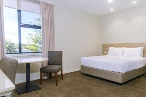 德文港Elimatta Hotel的一间卧室，里面有一张床、一张桌子和一扇窗户