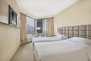 duas camas em um quarto de hotel com janela em The Kowloon Hotel em Hong Kong