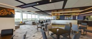 a dining room with tables and chairs and windows at JetPark Auckland Airport Hotel in Auckland