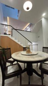 a table in a room with chairs and a staircase at Relax & Chill 4BR Terrace House in Batam Center