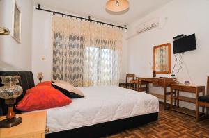 a bedroom with a bed and a desk and a window at Guesthouse Lanca in Tivat