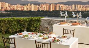 a table with white tables and chairs with a view of a city at Grand Walkerhill Seoul in Seoul