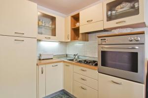 uma cozinha com armários brancos e um forno com placa de fogão em Apartment Tennis em Split