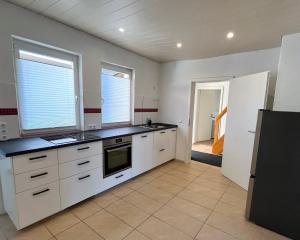 a kitchen with white cabinets and black counter tops at 90qm Ferienhaus Lorsch in Lorsch