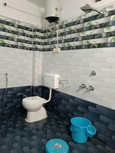 a bathroom with a toilet and a blue bucket at Shanti Sadan Homestay in Rājgarh