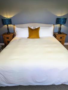 a large white bed with yellow pillows on it at The Cob House. in Ifton Heath