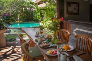 a table with food and drinks and a pool at Baruna Sari Villa in Ubud