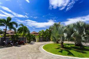 a group of motorcycles parked in a driveway with palm trees at Phuket Pool Residence - Adults only in Rawai Beach