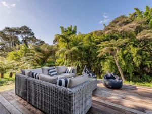 a wicker couch sitting on a wooden deck at Valley Hideaway - Kūaotunu Holiday Cabin in Kuaotunu