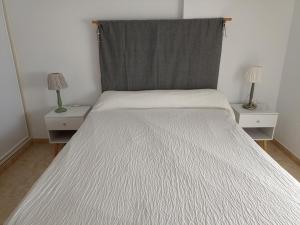sypialnia z białym łóżkiem i 2 szafkami nocnymi w obiekcie Apartamento en zona Atalaya con garaje y WIFI w mieście Conil de la Frontera