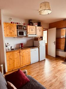 a kitchen with wooden cabinets and a white refrigerator at Les Edelweiss " les Balcons de Recoin" in Chamrousse