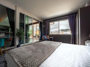 una camera da letto con un grande letto e una grande finestra di Grand Orlov Apart Hotel a Patong Beach Altre 84 foto