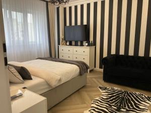 a bedroom with a bed and a television on a dresser at Studio Luxury Black & White in Alba Iulia