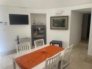 Un comedor con mesa y sillas y un televisor. en il Trullo di Alice e Chiara, en Selva di Fasano