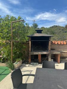 eine Terrasse mit einem gemauerten Kamin mit Tisch und Stühlen in der Unterkunft Casa Rural El Medico in Serradilla del Arroyo