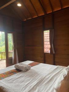 a bed in a wooden room with two towels on it at Uma d'Nyuh Homestay in Singaraja