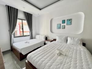 a bedroom with two beds and two windows at Cassie Boutique Hotel in Vung Tau
