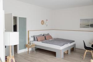 a white bedroom with a white bed with pillows at Frühstückshotel Fürstenwerth in Wilhelmshaven